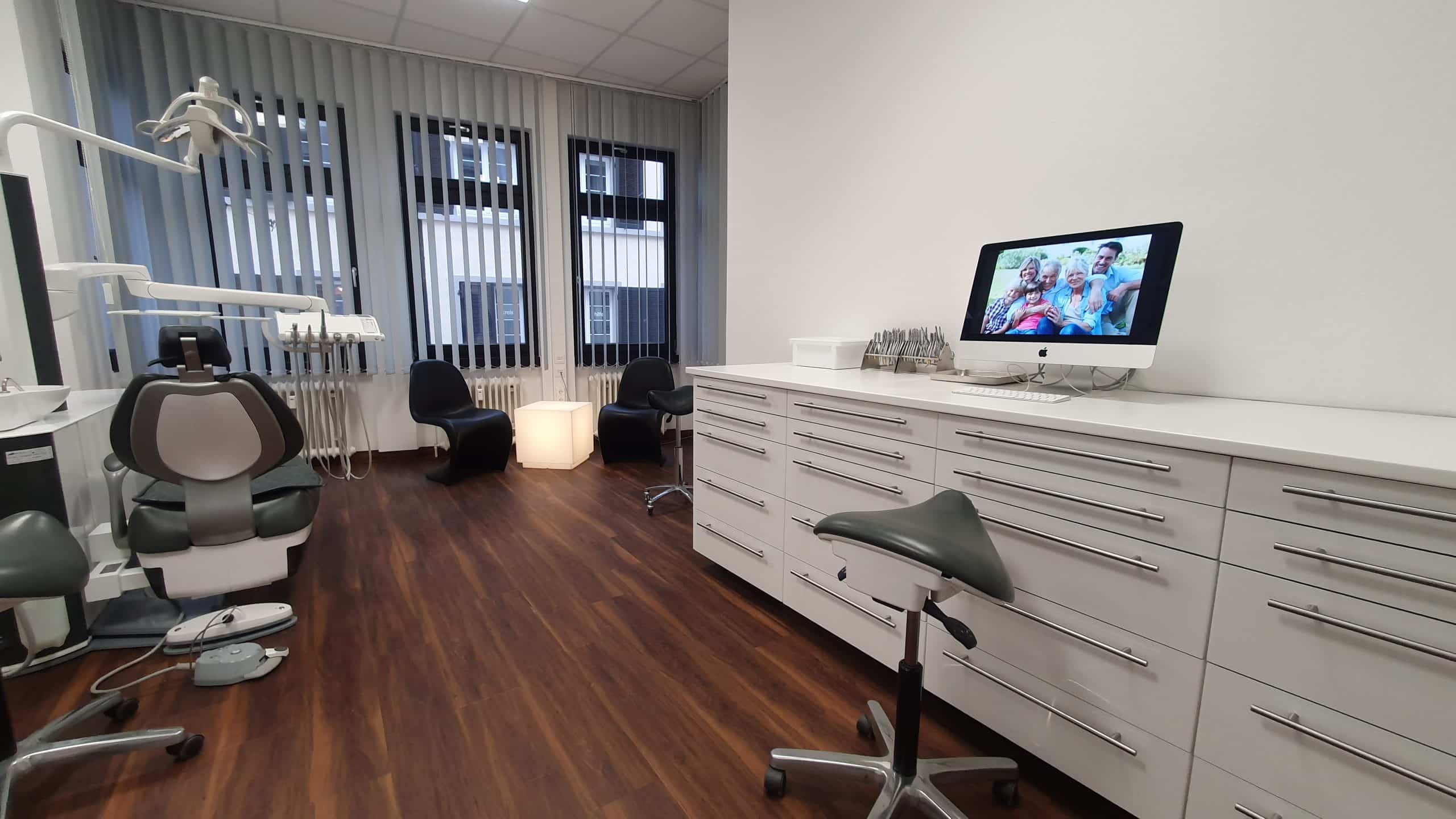 Kieferorthopädischer Behandlungsraum mit einem Computer, Stühlen und anderen medizinischen Geräten.